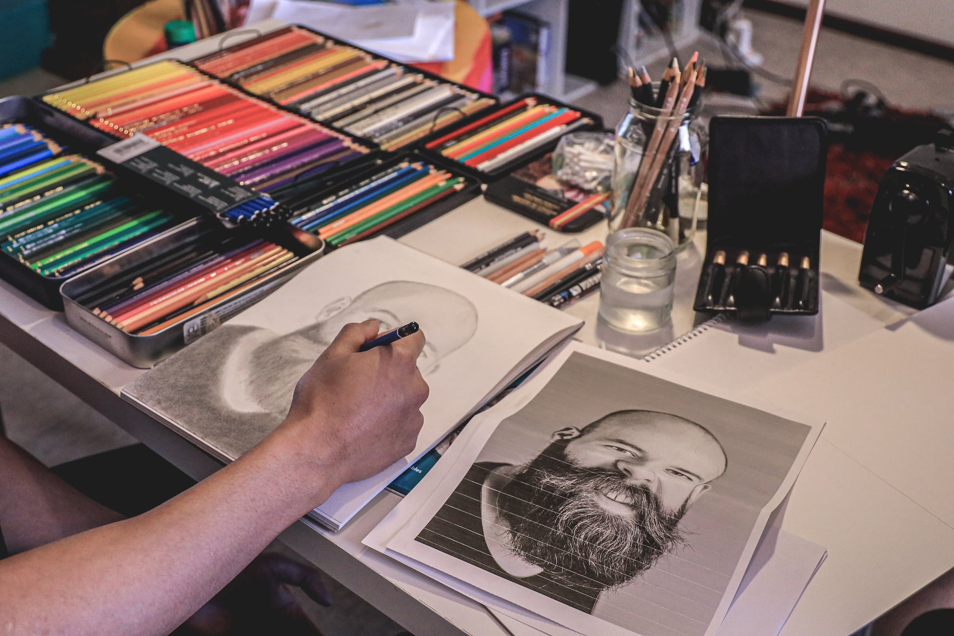 Emerging masterpiece: Luke's focused study, a graphite portrait taking shape, surrounded by the instruments of artistic magic.